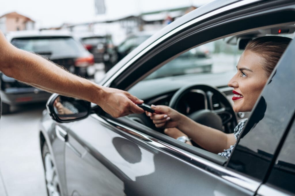 Woman behind wheel of a car being handed car key